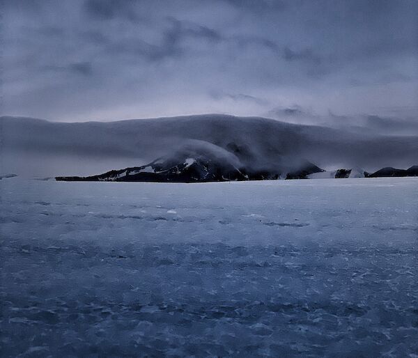 Portrait of a mountain in the distance with a cloud enveloping it