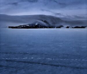 Portrait of a mountain in the distance with a cloud covering it