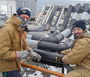 Two men fixing an outdoor pipe