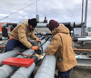 Two men fixing a pipe