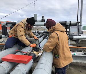 Two men fixing a pipe