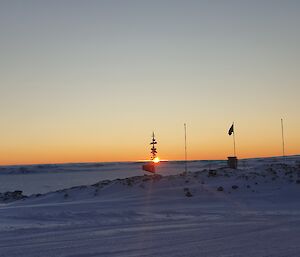 The sun rising through the Casey sign during winter at Casey