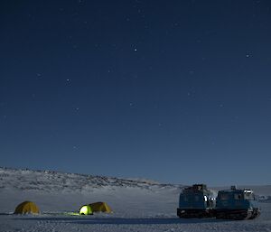 Two tents in snow during evening with Hagglund close by