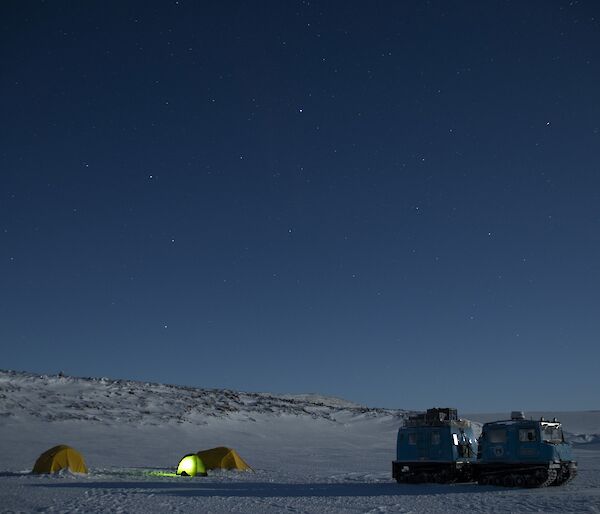 Two tents in snow during evening with Hagglund close by