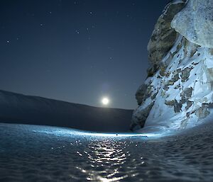 Tiger Rock with moon rising in background and ice patterns lit by torchlight