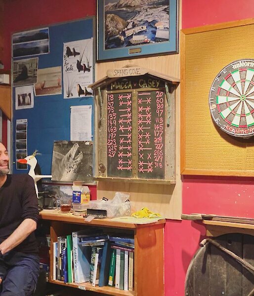 Expeditioneer sitting in front of the scoreboard and dartboard