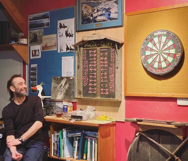 Expeditioneer sitting in front of the scoreboard and dartboard