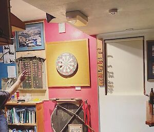 A player throwing a dart at the dartboard as team mate looks on from the side