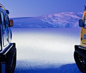 Two Hagglunds with light beams reflecting on to the snow and ice