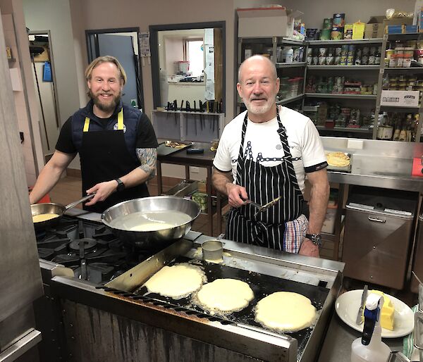 The Mawson Station kitchen with two men in aprons preparing pancakes
