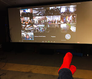 A TV screen showing the 16 person Zoom meeting