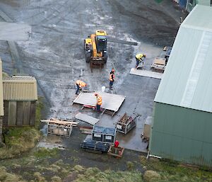 Aerial shot looking down on four workers separating roof sheets to recycle steel and timber