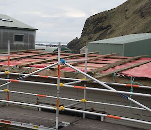 Close shot of scaffolding showing the temporary roof tarpaulin tied and weighed down with wood