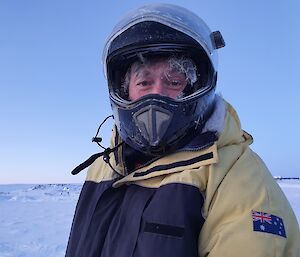 Expeditioner, in thick jacket and helmet, all frosty after a few hours out on the sea ice drilling