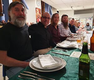 Expeditioners all looking to camera sitting at dining table ready for dinner