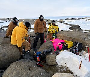 Rescuers surround the 'injured' expeditioner trapped between rocks
