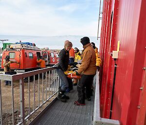 Rescuers carrying stretcher make way up some external stairs in to medical centre at the station