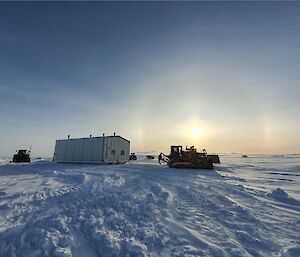 The wilkins mechanical workshop against a backdrop of sundogs or parhelion with diggers and work vehicles