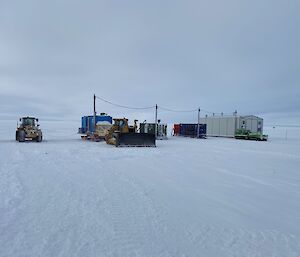 The laydown area at Wilkins with white shed building, blue container, digger and tractor