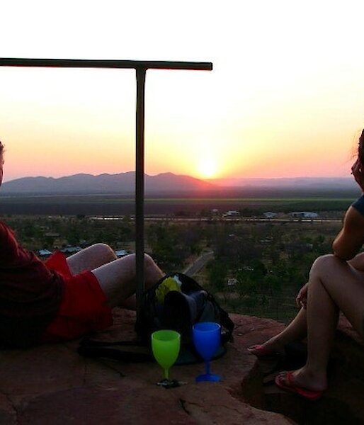 Two people sitting on a rock silouetted against a beautiful sunset