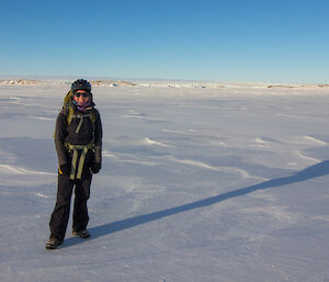 An expeditioner on the ice with a clear blue sky in the background