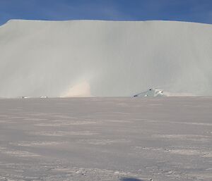 Large grounded iceberg, smoothed by the winds, on horizon against a blue sky
