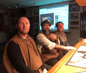 Three expeditioners sit at the station bar in Mediaeval peasant costumes