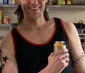 Tom Herbert with mullet and attitude, wearing a singlet and holding a drink, pre-haircut