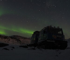 A Hägglund silhouetted against the sky with an Aurora display