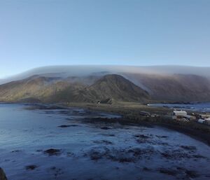 Smooth layer of cloud wrapped over the top of the island in the distance