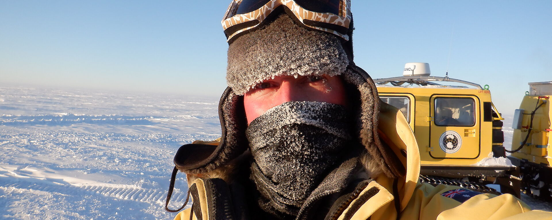 Portrait of expeditioner with cold weather gear.  Only eyes are uncovered on his face.  Ice in background.