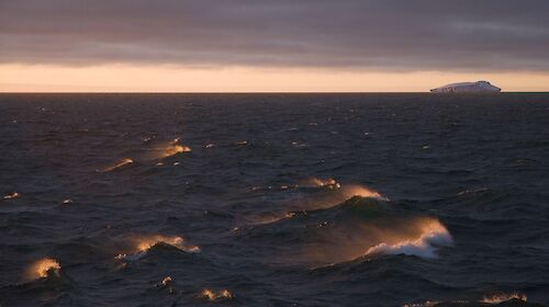 Waves in the Southern ocean with an iceberg in the background