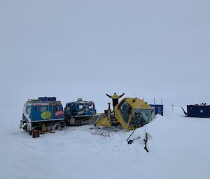 An expeditioner stands on a snow bound groomer with arms outspread, surrounded by Hagglunds