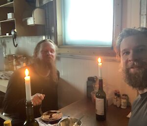 Two expeditioners sitting at the table in Bandit's hut with candles lit