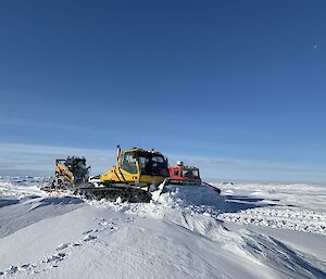 A snow groomer pushes snow as it drives next to the Hagglunds