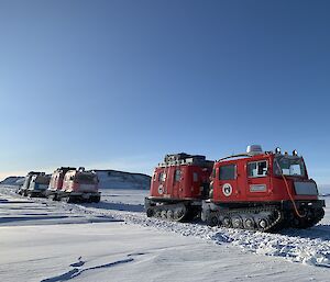A convoy of red, pink and blue Hagglunds