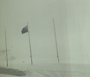 3 flag poles in the ice with a blizzard around them
