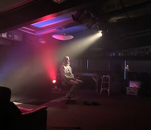 man sits on stage with coloured lights