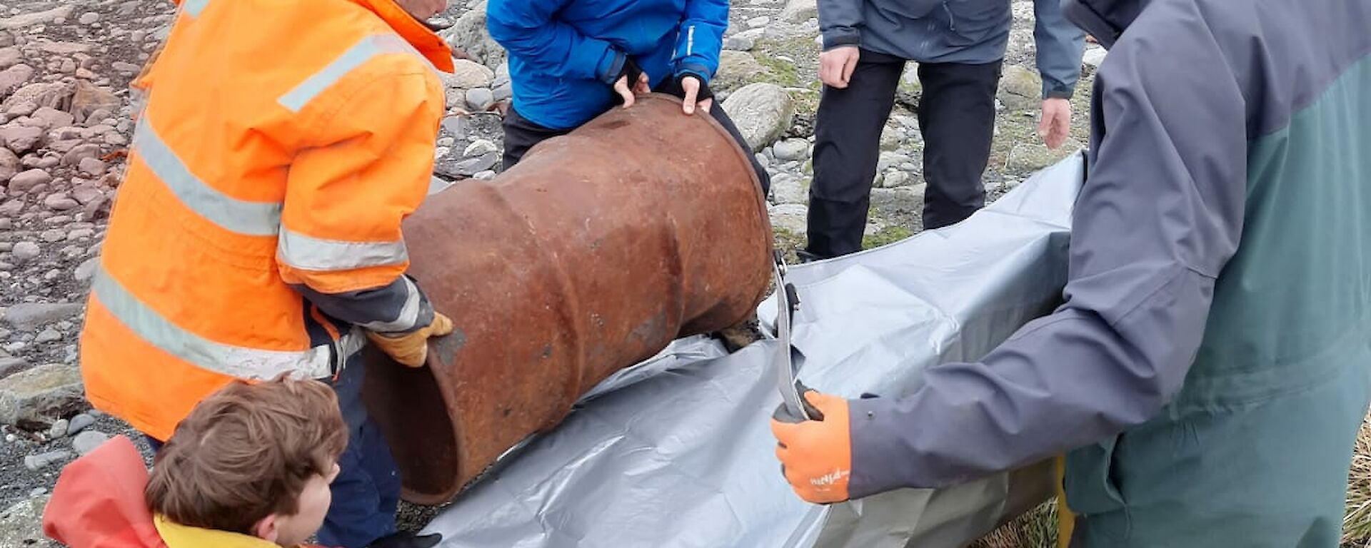 The fuel drum is loaded into the stretcher by keen members of the search and rescue team