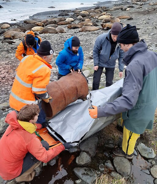 The fuel drum is loaded into the stretcher by keen members of the search and rescue team