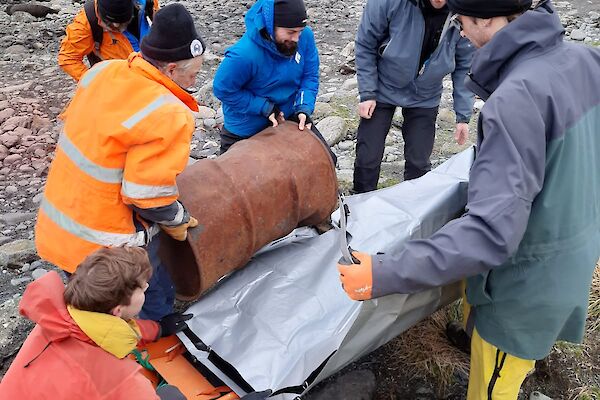 The fuel drum is loaded into the stretcher by keen members of the search and rescue team