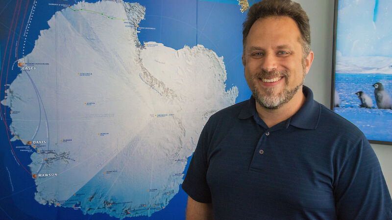Dr Kool standing in front of an Antarctic map.
