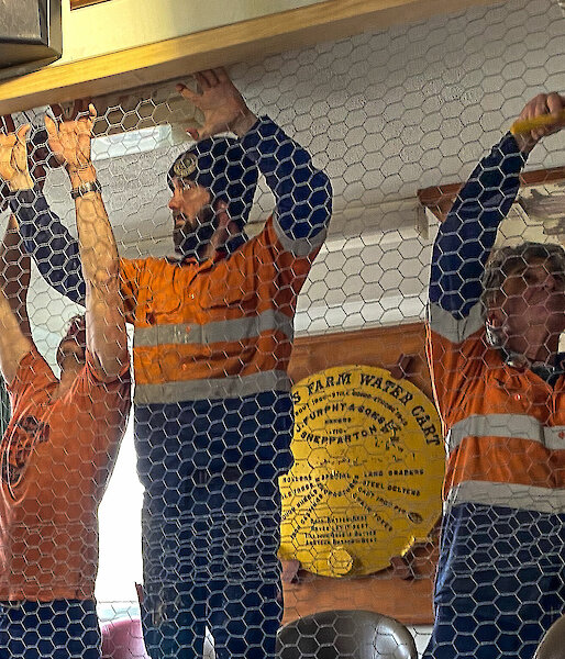 Three tradesmen putting up a chicken wire wall in the Mess