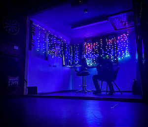 Silhouette of a man playing guitar with fairy lights behind him