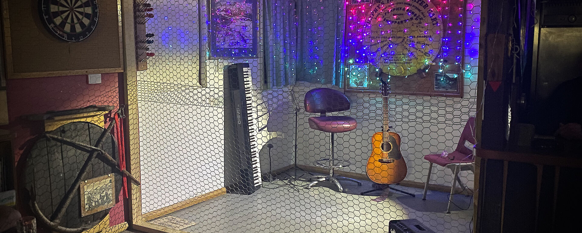 Stage with chicken wire wall in front and fairy lights on back wall