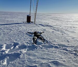 Expeditioner lies on their back in a star shape in the deep snow