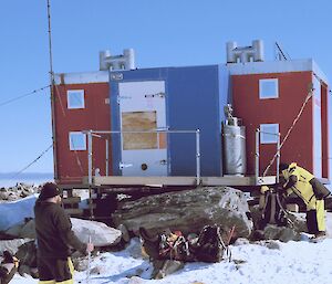 Jack's hut near Casey station with two expeditioners in front with backpacks