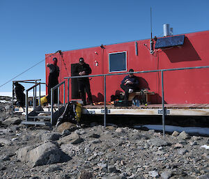 Robbo's hut on Robinsons Ridge near Casey station.  Expeditioners rest on a deck outside.