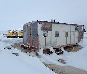 Wilkes hut on Stonehocker Point near Casey station.  Yellow Hägglunds at rear.