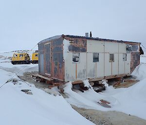 Wilkes hut on Stonehocker Point near Casey station.  Yellow Hägglunds at rear.